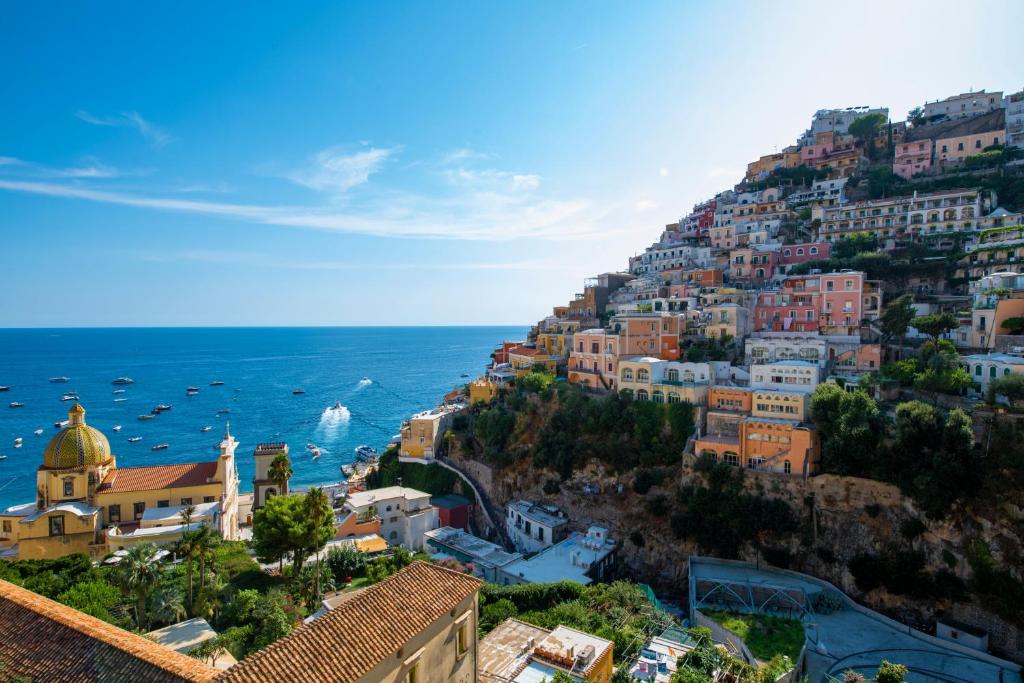 Blick auf eine Stadt auf einem Hügel mit dem Meer in der Unterkunft Hotel Savoia in Positano