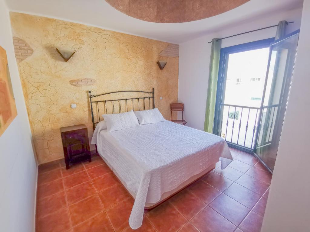 a bedroom with a white bed and a large window at Paradise Villa in Corralejo