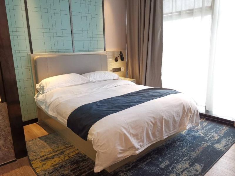 a bed in a bedroom with a large window at GreenTree Eastern Lianyungang Jiaruibao Plaza Hotel in Lianyungang