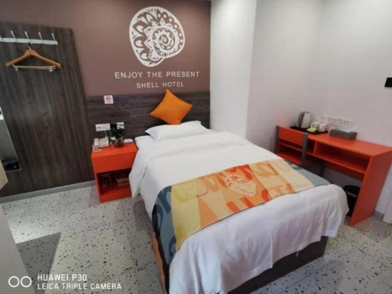een slaapkamer met een bed en twee bureaus en een bord bij Shell Hefei Yaohai Distrct Baida Zhougudui Daxing RoadHotel in Hefei