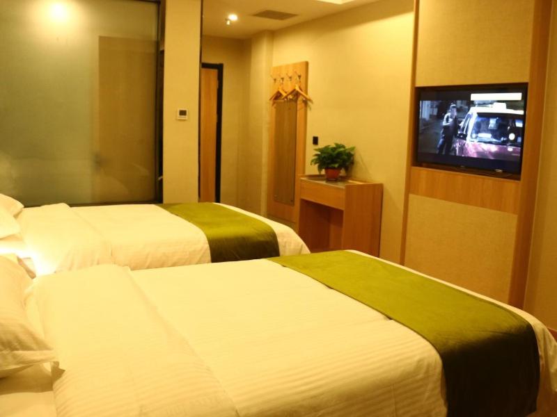a hotel room with two beds and a tv at GreenTree Inn Heze Cao County Railway Station Business Hotel in Cao