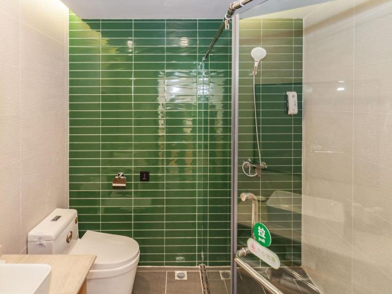a green tiled bathroom with a toilet and a shower at GreenTree Inn Dalian Airport New District Xinzhaizi Express Hotel in Dalian