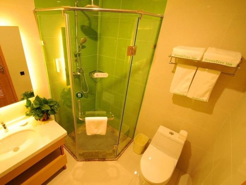 a bathroom with a shower and a toilet and a sink at GreenTree Inn Langfang Bazhou City Tangeerli Town Spa Business Hotel in Langfang