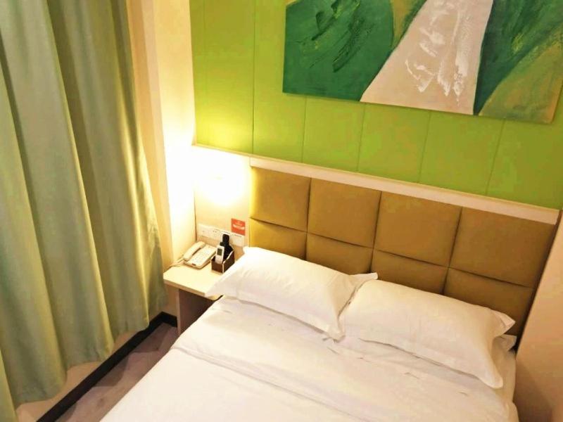 1 dormitorio con cama blanca y pared verde en Shell Wuhan city Wuhan University Hotel en Wuhan