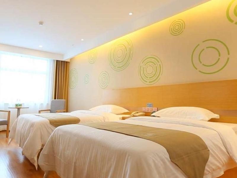 um quarto de hotel com três camas com lençóis brancos em GreenTree Inn Taizhou Taixing City Xuanbao Town Zhongyang Road Express Hotel em Yong'anzhou