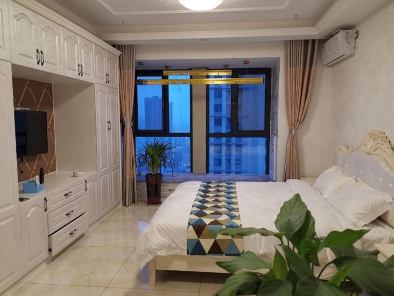 1 dormitorio con cama grande y ventana grande en Green Apartments Suqian Shuyang Central City Plaza Hotel, en Suqian