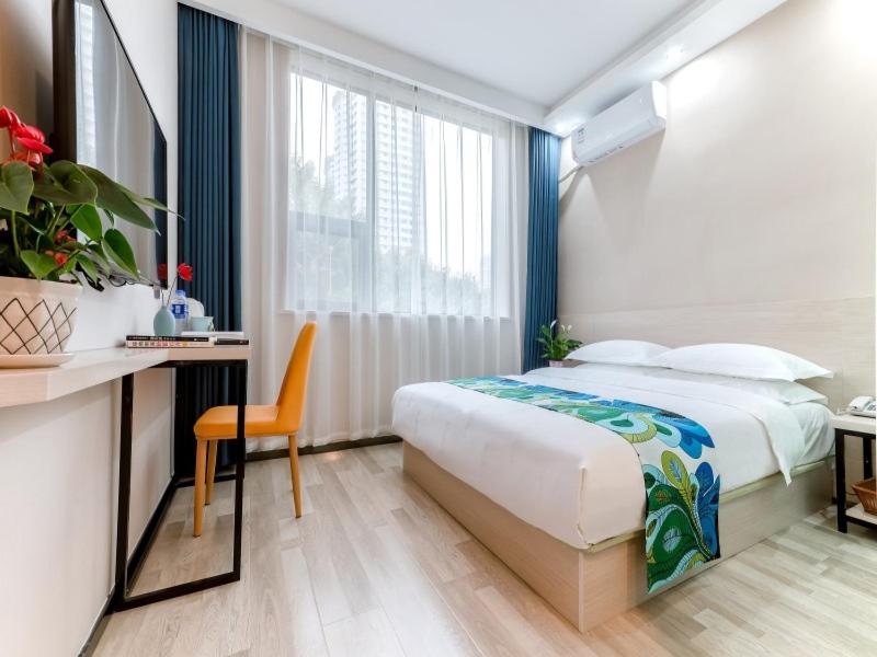 a bedroom with a bed and a desk and a window at Shell Xi'an Yanta District Jixiang Village Subway Entrance Hotel in Xi'an