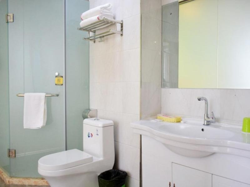 a white bathroom with a toilet and a sink at Shell Taiyuan Xiaodian District Shanxi Hospital Hotel in Taiyuan