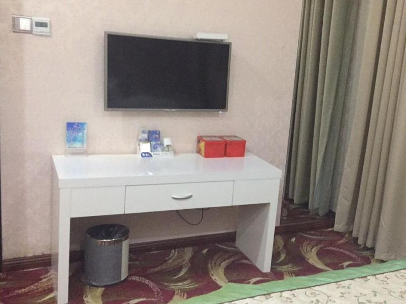 a white desk with a television on a wall at GreenTree Alliance Bengbu Railway Station Hotel in Bengbu