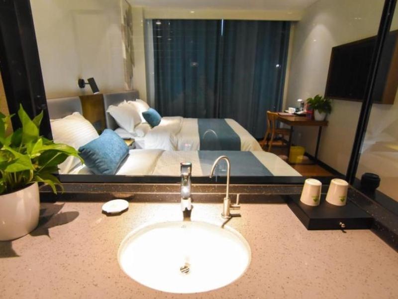 a bathroom with a sink in front of a bed at GreenTree Rizhao Lanshan Coach Station Hotel in Rizhao