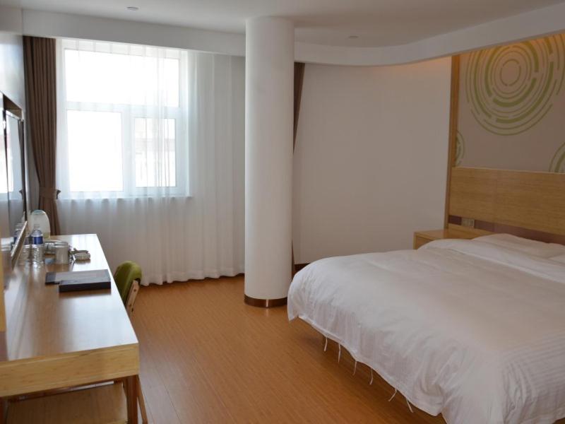 a bedroom with a white bed and a desk and a window at GreenTree Inn Tangshan Lubei District Hancheng Likang Hospital Express Hotel in Tangshan