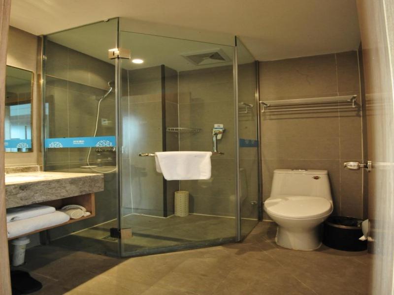 a bathroom with a glass shower and a toilet at VX Zibo Zhangdian District Jinjing Avenue Hotel in Zibo