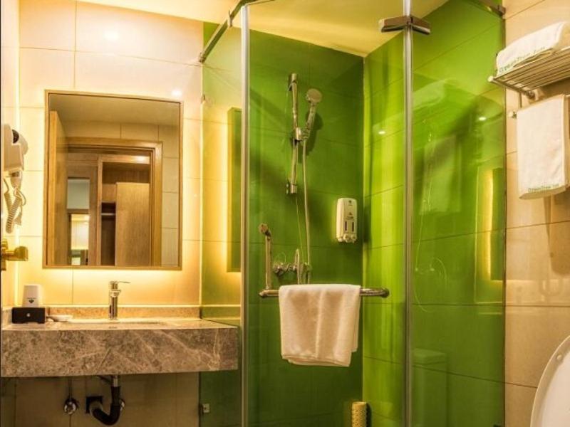 a green bathroom with a sink and a shower at GreenTree Inn Tangshan Road North District Xishan Road Business Hotel in Tangshan