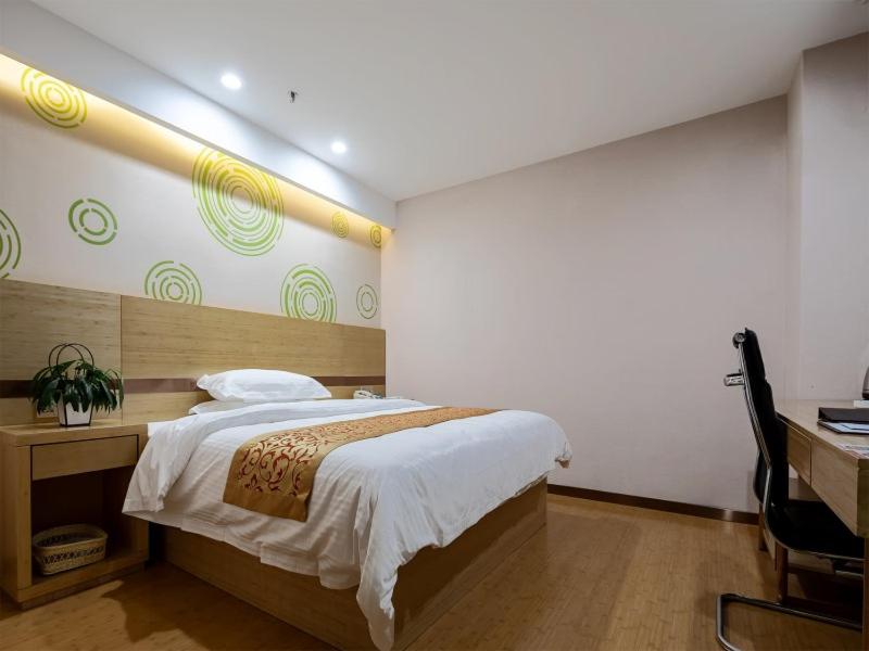 a bedroom with a large bed and a desk and a desk at GreenTree Inn Changzhou Menghe Town Chengfeng Building Business Hotel in Changzhou