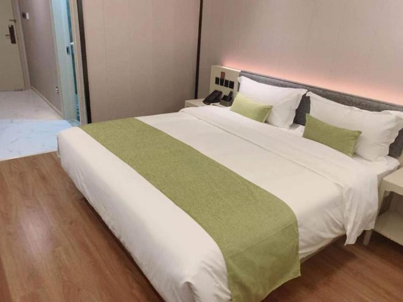 a large white bed with green and white pillows at Gya Jiaxing Pinghu City Wuyue Square Shengli Road Hotel in Jiaxing