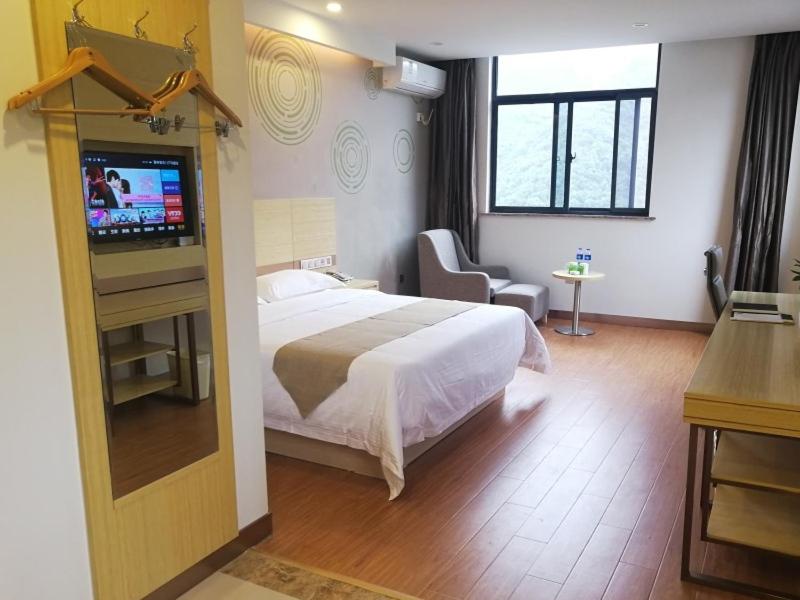 a hotel room with a bed and a television at GreenTree Inn Chizhou Shitai County Government Affairs New District Business Hotel in Chizhou