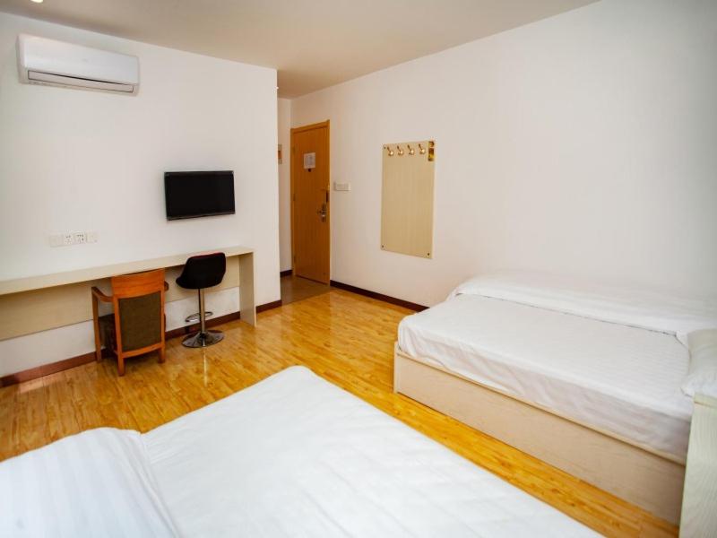a bedroom with two beds and a desk and a television at Shell Huai'an Fishing Hook Town Hotel in Huai'an