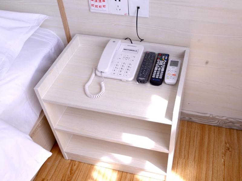 un tavolo con un telefono e telecomandi di Shell Xingtai City Qiaodong DistrictXinhua South Road Hotel a Xingtai