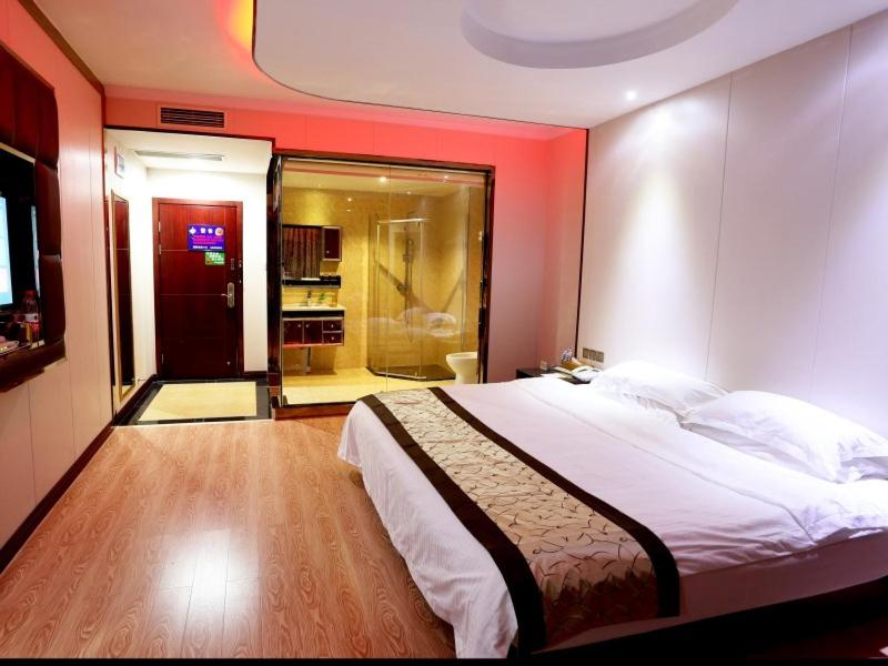 una camera da letto con un letto grande con una parete rossa di GreenTree Alliance Jinhua Dongyang East Bus Station Dongyong Road Hotel a Dongyang