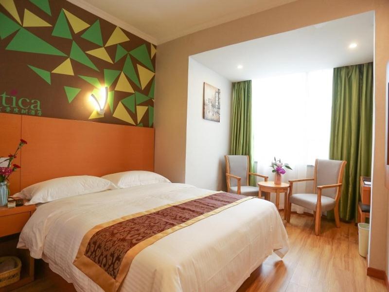 a bedroom with a large bed and a table and chairs at Vatica Hefei Lujiang Road Hotel in Hefei