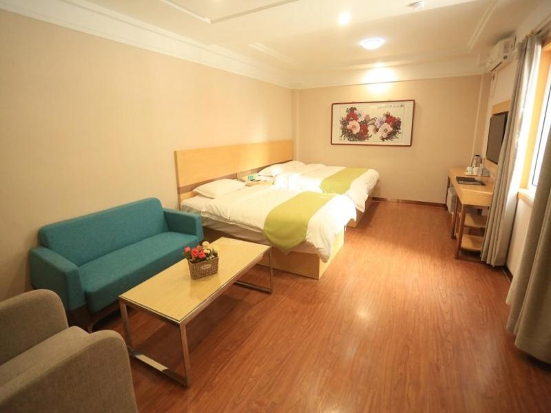 a hotel room with a bed and a couch and a table at Green Alliance Chengde City Shuangqiao District Summer Resort Hotel in Chengde