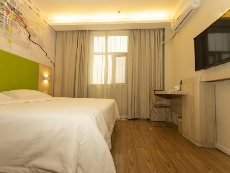 a hotel room with a bed and a television at Vatica Bozhou City Railway Station Hotel in Bozhou