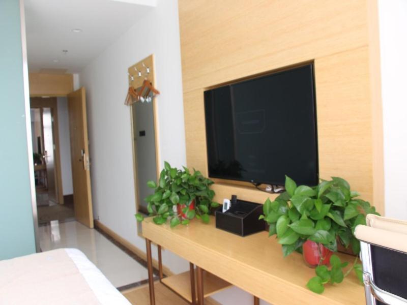 un salon avec une télévision et des plantes sur une table dans l'établissement GreenTree Inn Langfang Dachang Movie City Select Hotel, à Dachang