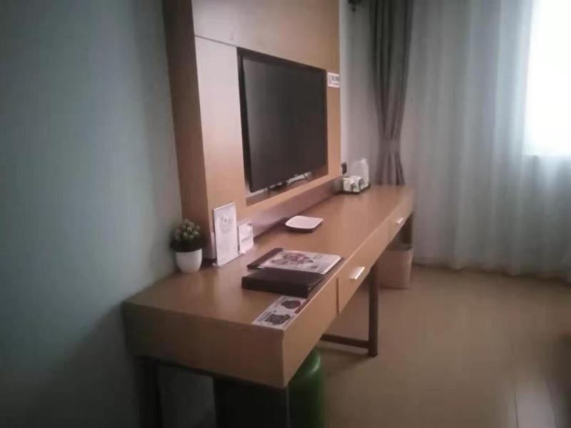 einen Schreibtisch mit einem TV darüber in einem Zimmer in der Unterkunft GreenTree Inn Shanghai Jinshan District Wanda Plaza Longhao Road Express Hotel in Huinan