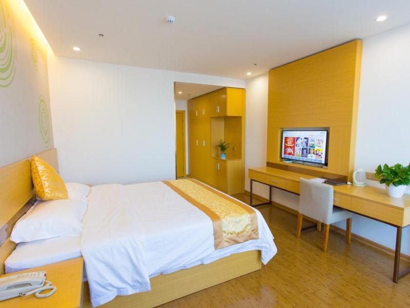 a bedroom with a bed and a desk and a television at GreenTree Inn Cixi Zhouxiang Town Jiayue Plaza Business Hotel in Cixi
