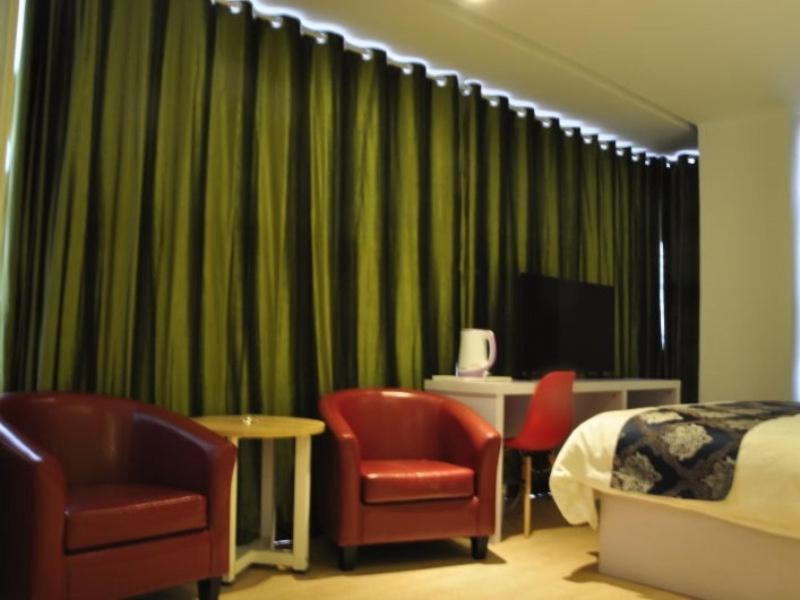 a hotel room with two chairs and a bed and a television at Shell Jinan Gaoxin District Shunhua Road Qilu Software Park Hotel in Jinan