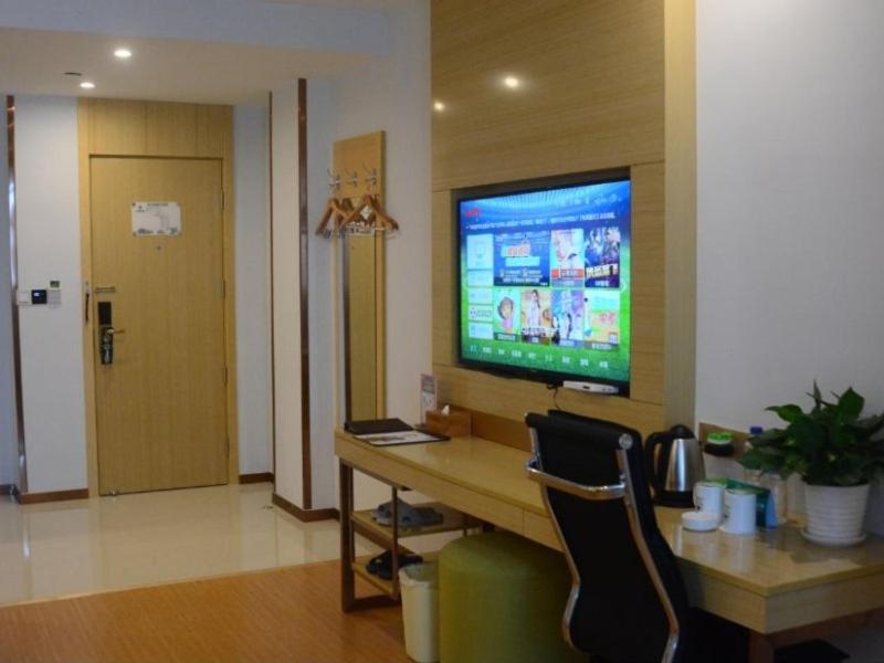 a room with a desk with a television on a wall at GreenTree Inn LuAn Yeji District Yeji Railway Station Express Hotel in Sifangtang