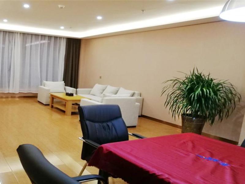 sala de estar con mesa, sillas y sofá en GreenTree Inn Yulin South Changcheng Road Business Hotel, en Yulin
