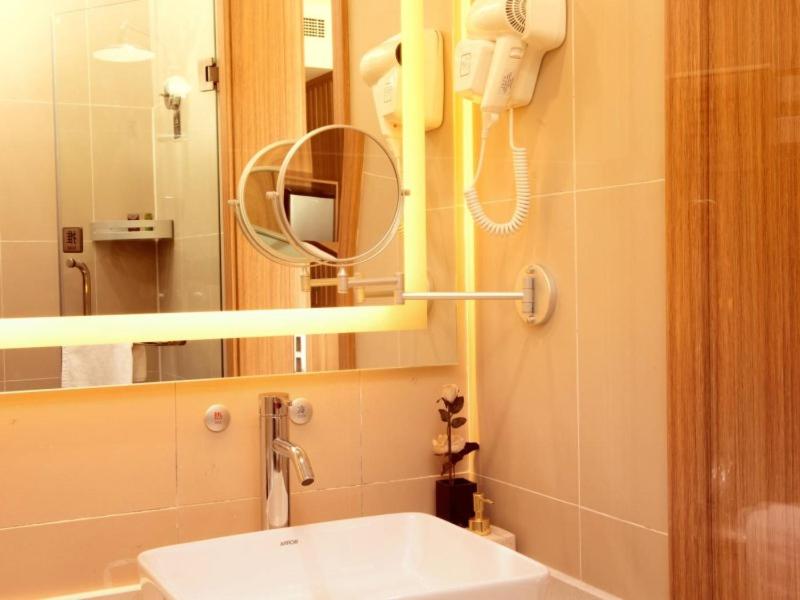 a bathroom with a sink and a mirror and a phone at GreenTree Eastern Tianjin Wuqing Stadium Hotel in Tianjin