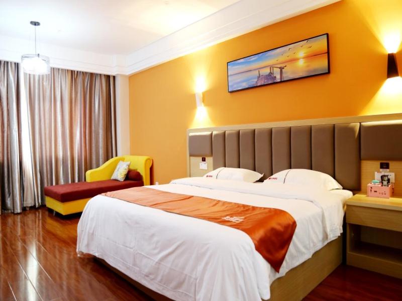 a hotel room with a large bed and a chair at Shell Fuzhou Dongxiang District Railway Station Longshan South Road Hongxin Trade City Hotel in Fuzhou