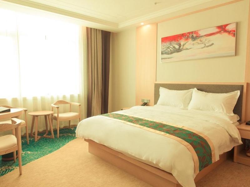 a hotel room with a large bed and a table at GreenTree Eastern Fuyang Yingdong District South Guoyang Road Hotel in Fuyang