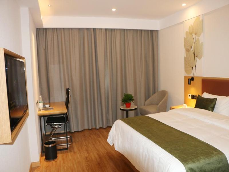 une chambre d'hôtel avec un lit, un bureau et une télévision dans l'établissement GreenTree Inn Anqing City Huai Ning County Wanhe Road Select Hotel, à Qianshan