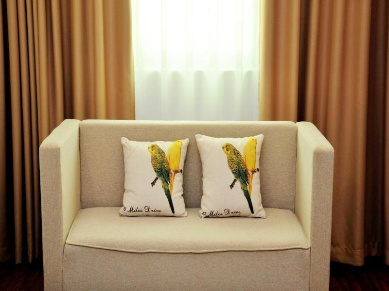 a white couch with two pillows with a parrot on it at GreenTree Inn Dongfang City Dongfang Avenue High-speed Railway Station Express Hotel in Dongfang