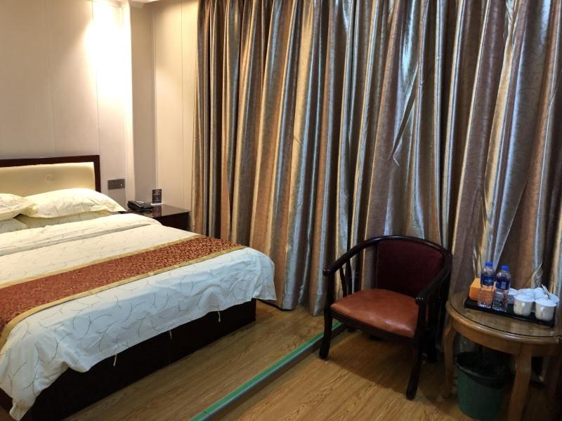 a bedroom with a bed and a chair and a table at Shell Quanzhou City Hui'an County Xinhongxing Hotel in Quanzhou