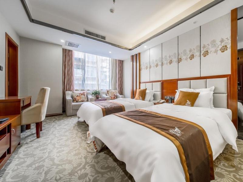 a hotel room with two beds and a desk at GreenTree Eastern Kunming Baiyun Road Tongde Square Hotel in Kunming