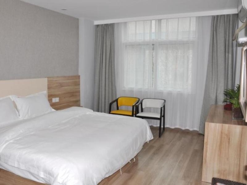 a bedroom with a bed and two chairs and a window at Shell Suzhou Yongqiao District Dongchang Road National Purchase Square Hotel in Suzhou