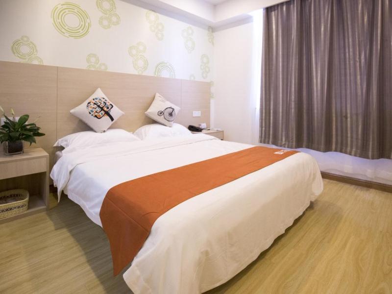 a bedroom with a large bed in a room at Shell Huaian Xiamen Road Hotel in Huai'an