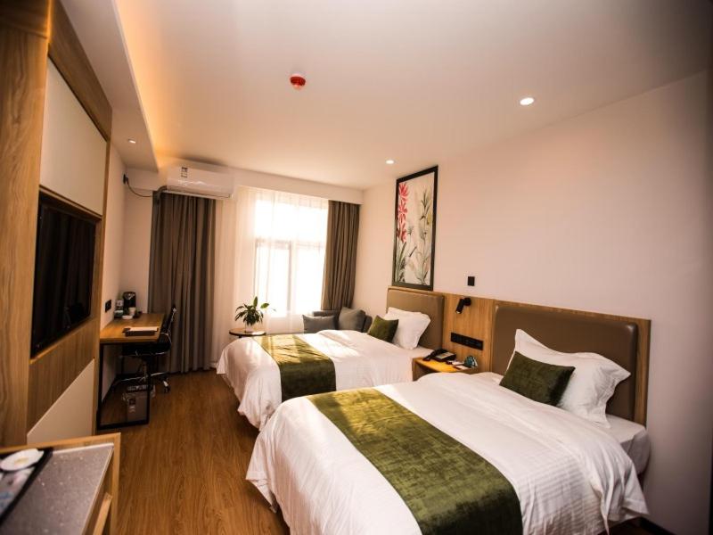 um quarto de hotel com duas camas e uma televisão em GreenTree Inn Qingdao Huangdao District Jinshatan Road Jinshatan Hotel em Beizhuang