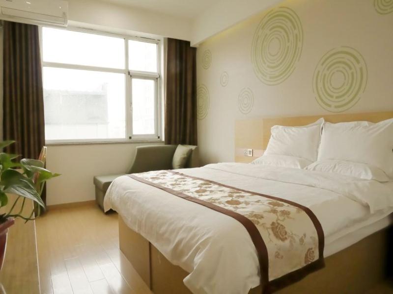 ein Schlafzimmer mit einem großen Bett und einem Fenster in der Unterkunft GreenTree Inn Shijiazhuang Qiaoxi District Zhongshan Road Xili Street Express Hotel in Shijiazhuang