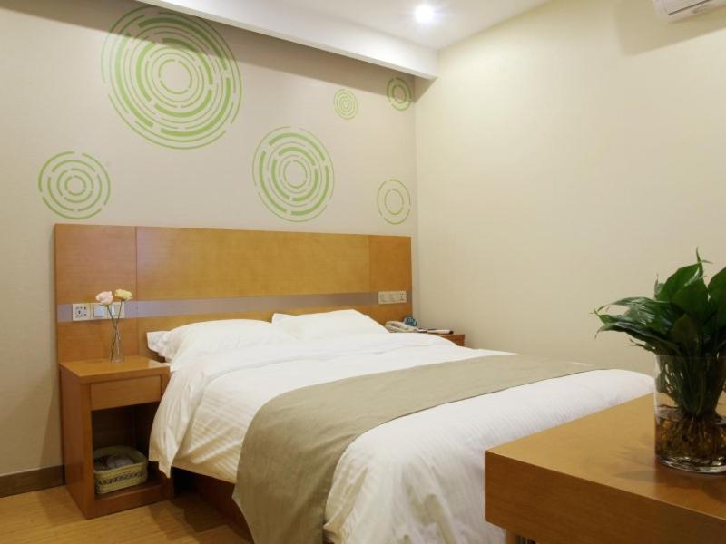 Schlafzimmer mit einem großen Bett mit einem Kopfteil aus Holz in der Unterkunft GreenTree Inn ShanghaiBaoshan District Tieshan Road Youyi Road Hotel in Baoshan