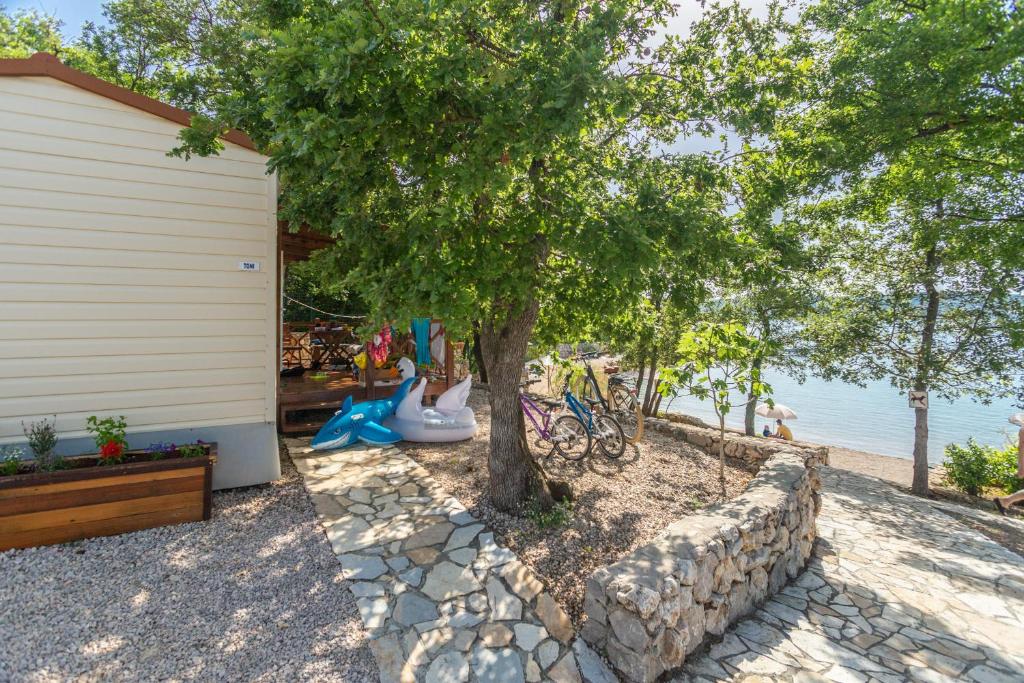 a house with a tree and a stone wall at Krk Mobile Homes in Klimno