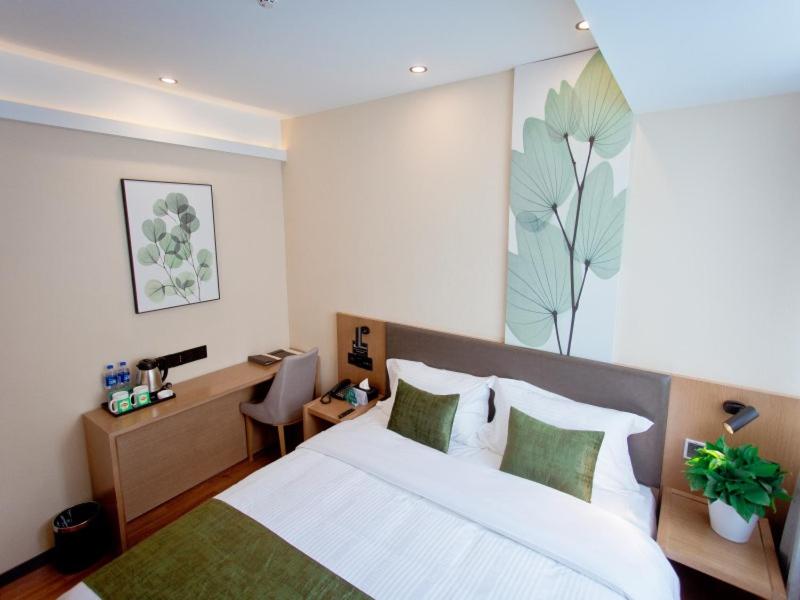 a bedroom with a large white bed and a desk at GreenTree Inn Fuyang City Yingzhou District Kuixing Road Business Hotel in Fuyang