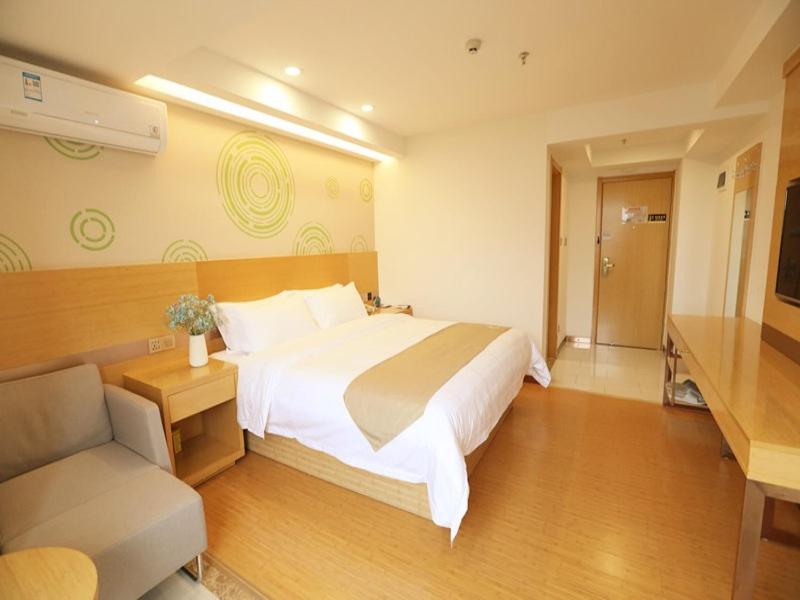 a bedroom with a large bed and a couch at GreenTree Inn Haikou Chengmai Old Town Software Park Business Hotel in Bailian