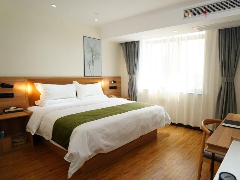 GreenTree Inn Lu'an G312 National Road Jintaiyang Motor City Select Hotel في Lu'an: غرفة نوم بسرير كبير ونافذة