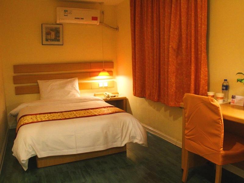 a bedroom with a bed and a desk and a chair at Shell Xinyu City Railway Station Plaza Hotel in Xinyu