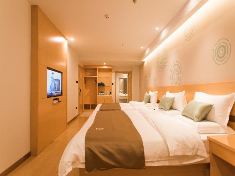 a large bed in a hotel room with a television at GreenTree InnZhangjiakou High-speed Railway Station Business Hotel in Zhangjiakou